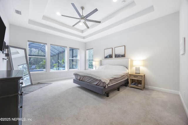 carpeted bedroom featuring ceiling fan and a tray ceiling