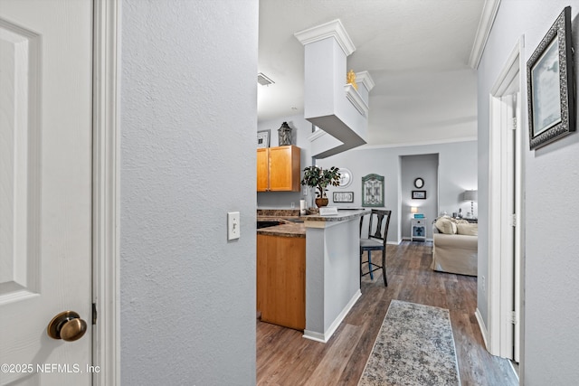 kitchen featuring kitchen peninsula, a breakfast bar, dark hardwood / wood-style floors, and ornamental molding