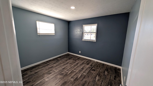 spare room with dark hardwood / wood-style floors and a textured ceiling