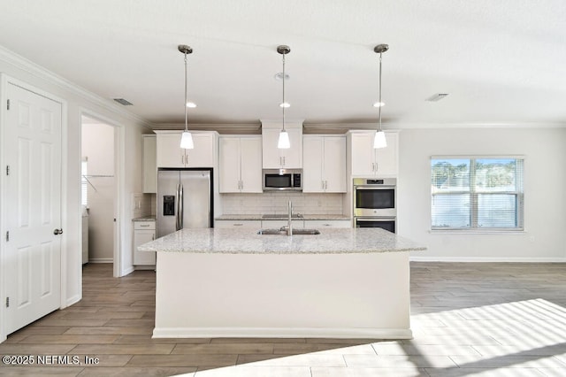 kitchen featuring white cabinets, appliances with stainless steel finishes, light stone countertops, and a kitchen island with sink