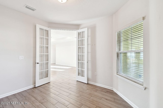 unfurnished room with light hardwood / wood-style floors and french doors