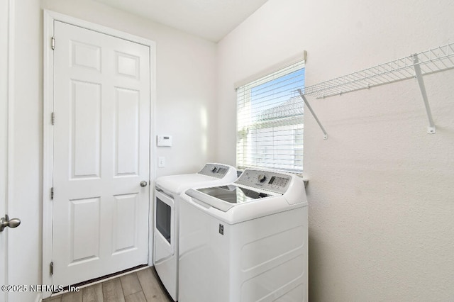 laundry room featuring light wood-type flooring and separate washer and dryer