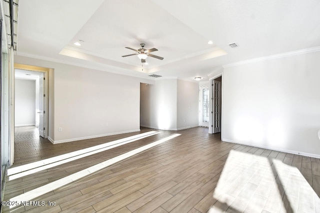 spare room with ceiling fan, a tray ceiling, and crown molding