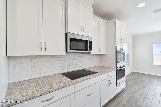 kitchen featuring stainless steel appliances, white cabinetry, crown molding, and light stone counters