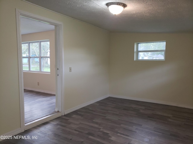 spare room featuring dark wood-type flooring and a textured ceiling