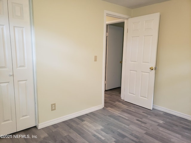 unfurnished bedroom featuring a closet and dark wood-type flooring