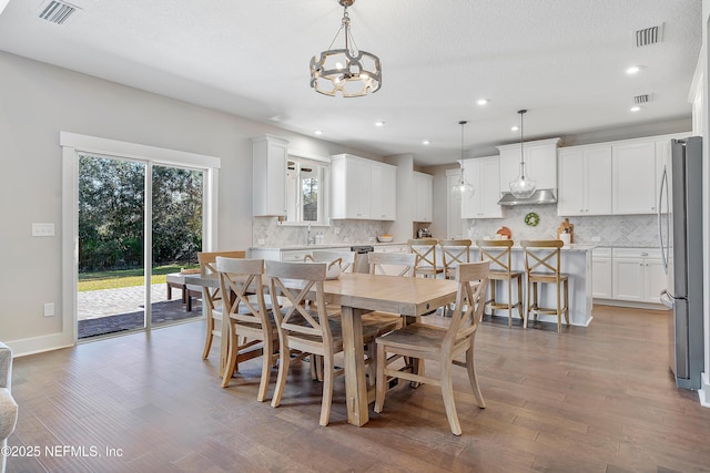 dining area featuring a textured ceiling, an inviting chandelier, hardwood / wood-style flooring, and sink