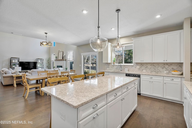 kitchen with a center island, decorative light fixtures, white cabinetry, sink, and stainless steel dishwasher