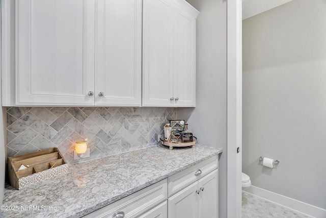 kitchen with white cabinets, tasteful backsplash, and light stone countertops