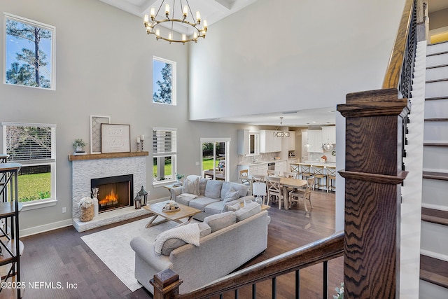 living room with dark wood-type flooring, a fireplace, a towering ceiling, and a notable chandelier