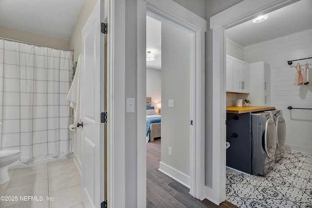 bathroom featuring tile patterned flooring, washer and clothes dryer, toilet, and wooden walls