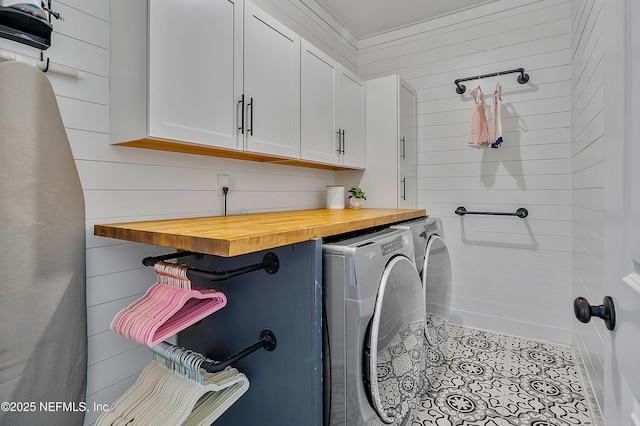 washroom featuring light tile patterned flooring, washer and dryer, wood walls, and cabinets