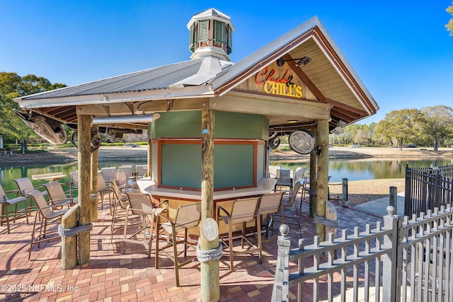 dock area featuring a patio, a water view, a gazebo, and exterior bar