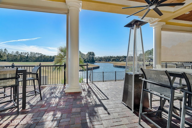 view of patio with ceiling fan, a water view, and exterior bar