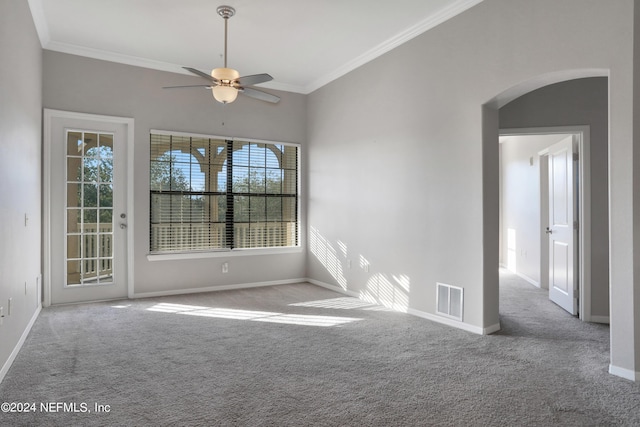 carpeted spare room featuring ceiling fan, a wealth of natural light, and ornamental molding