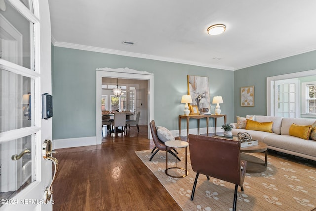 living room with hardwood / wood-style floors, ornamental molding, and an inviting chandelier