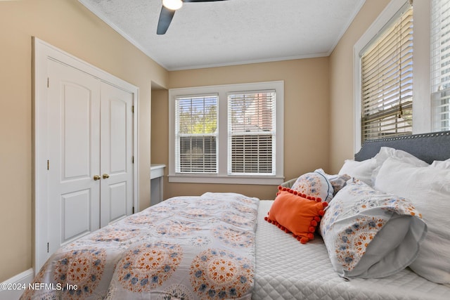 bedroom featuring ceiling fan, ornamental molding, a textured ceiling, and a closet