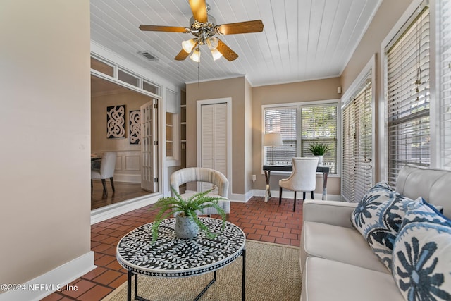 living room featuring ceiling fan, dark tile patterned floors, ornamental molding, and wooden ceiling