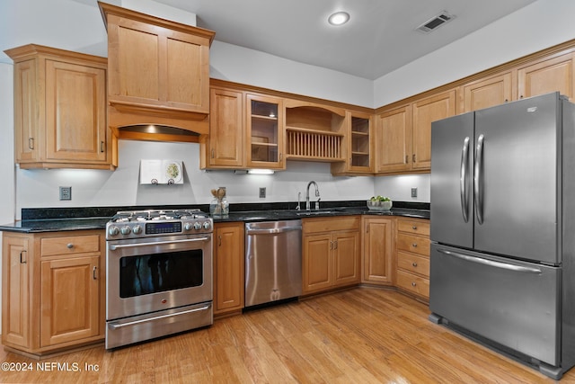 kitchen featuring dark stone countertops, sink, light hardwood / wood-style floors, and stainless steel appliances