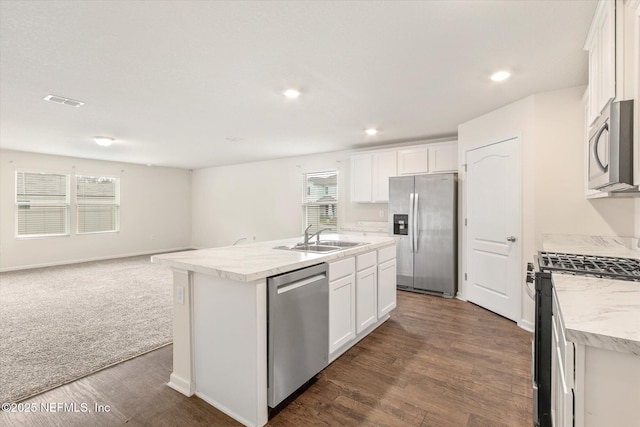 kitchen with white cabinetry, sink, dark wood-type flooring, stainless steel appliances, and an island with sink