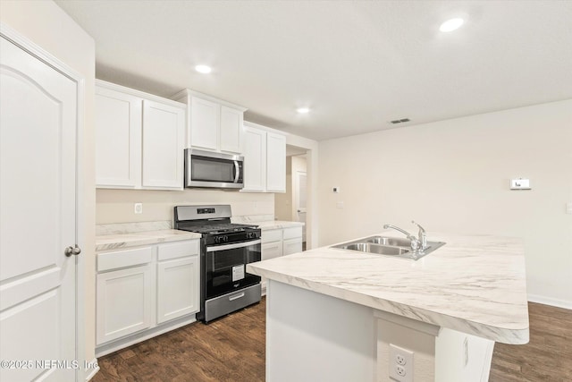 kitchen with white cabinetry, sink, dark hardwood / wood-style flooring, an island with sink, and appliances with stainless steel finishes