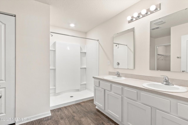 bathroom featuring vanity, a shower, wood-type flooring, and a textured ceiling