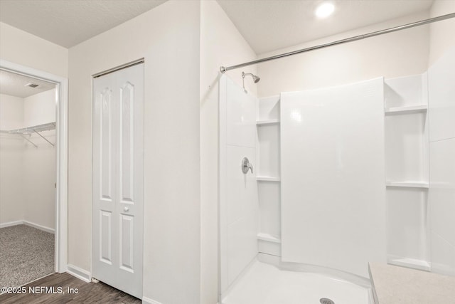 bathroom with hardwood / wood-style floors, walk in shower, and a textured ceiling