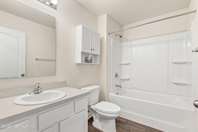 full bathroom with hardwood / wood-style floors, vanity, bathing tub / shower combination, toilet, and a textured ceiling