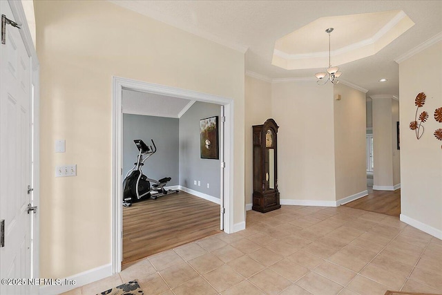 workout area featuring light tile patterned floors, ornamental molding, a tray ceiling, and a notable chandelier