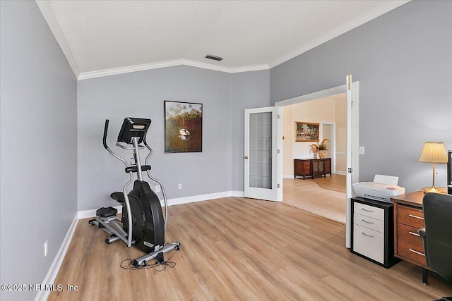 exercise area featuring a textured ceiling, vaulted ceiling, french doors, ornamental molding, and light wood-type flooring