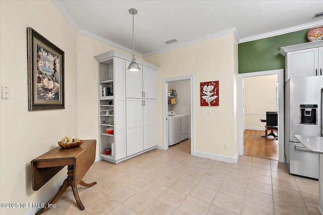 dining space with independent washer and dryer, a textured ceiling, light tile patterned flooring, and ornamental molding