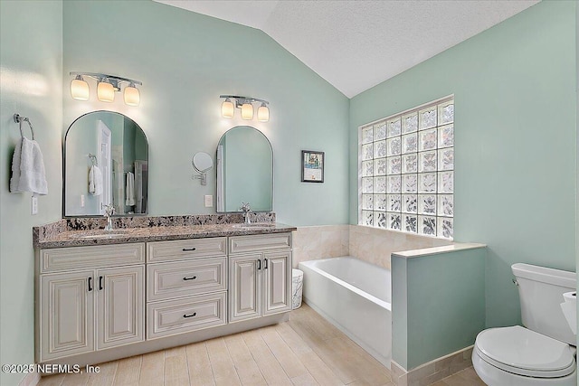 bathroom featuring a tub, toilet, vanity, a textured ceiling, and lofted ceiling