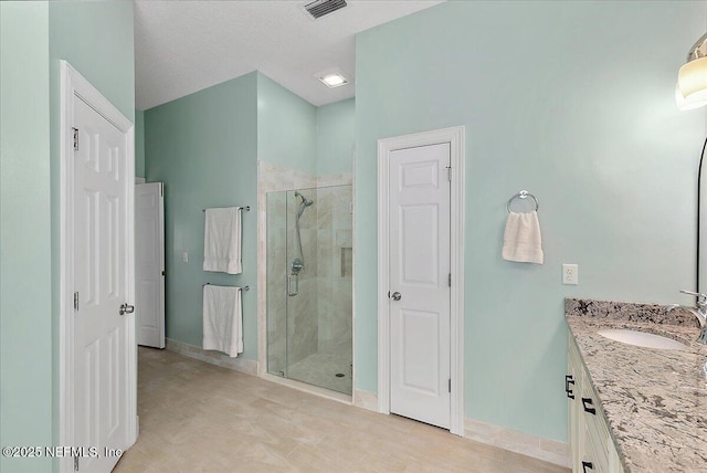 bathroom featuring a textured ceiling, walk in shower, and vanity