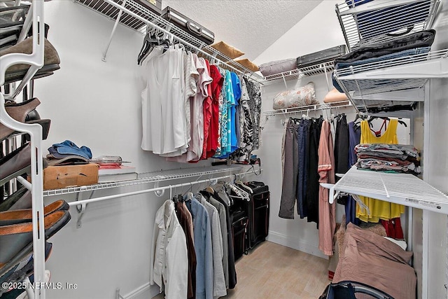 walk in closet featuring light wood-type flooring and vaulted ceiling