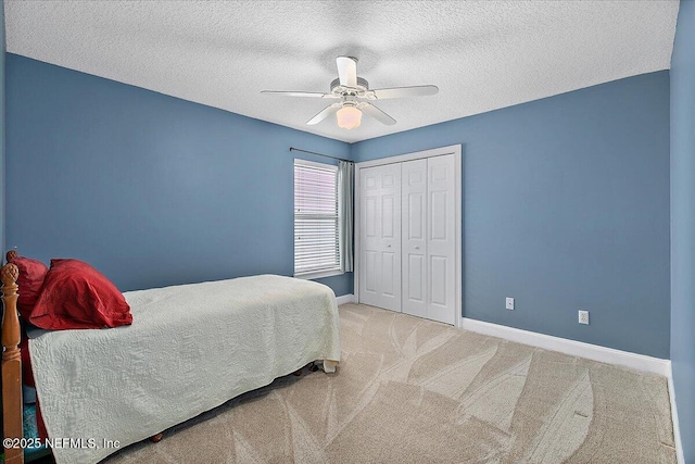 carpeted bedroom with a textured ceiling, ceiling fan, and a closet