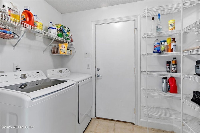 washroom with a textured ceiling, light tile patterned floors, and washer and clothes dryer