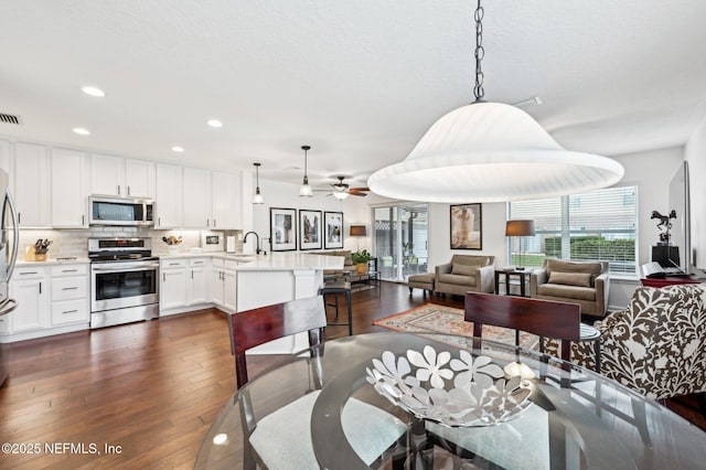 dining area with sink, dark wood-type flooring, and ceiling fan