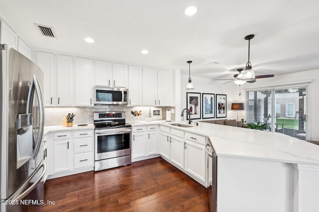 kitchen featuring sink, kitchen peninsula, white cabinets, and appliances with stainless steel finishes