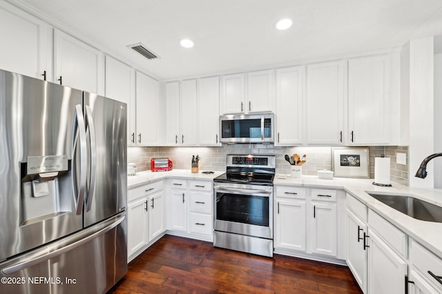 kitchen with white cabinetry, appliances with stainless steel finishes, sink, and backsplash