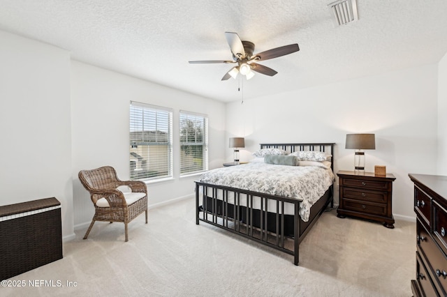 bedroom featuring light carpet, a textured ceiling, and ceiling fan