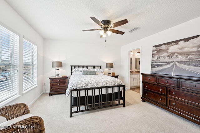 carpeted bedroom featuring ceiling fan, ensuite bath, and a textured ceiling