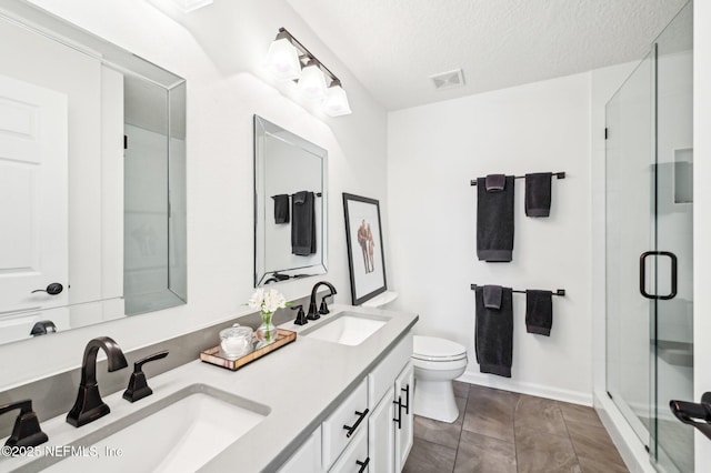 bathroom featuring tile patterned floors, toilet, a shower with shower door, a textured ceiling, and vanity