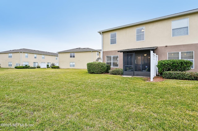 rear view of property featuring a sunroom and a yard