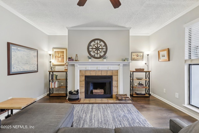 unfurnished living room with a tiled fireplace, crown molding, ceiling fan, and wood finished floors