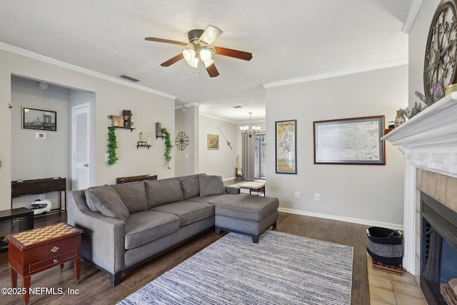 living room featuring visible vents, baseboards, ornamental molding, ceiling fan with notable chandelier, and a tile fireplace