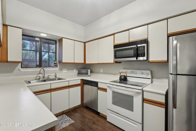 kitchen with a sink, stainless steel appliances, light countertops, a textured ceiling, and white cabinetry