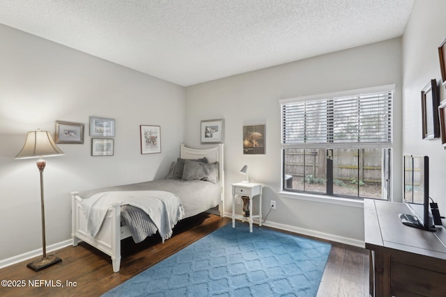 bedroom with a textured ceiling, baseboards, and wood finished floors