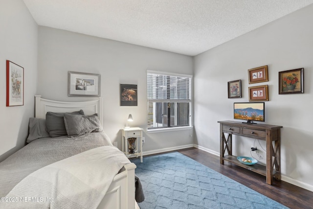 bedroom with dark wood-type flooring, baseboards, and a textured ceiling