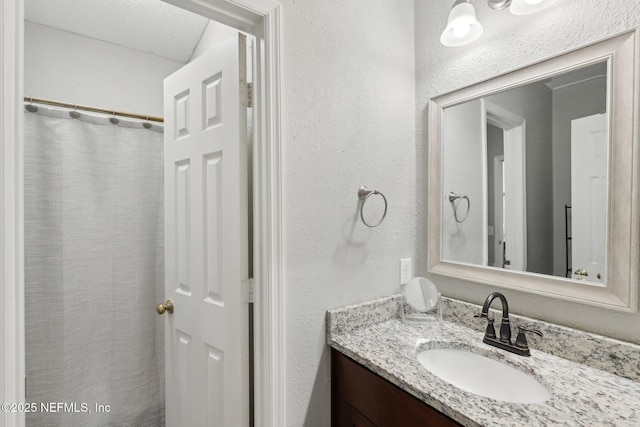 full bathroom with vanity and a textured wall