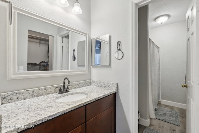 full bath with vanity, baseboards, and wood finished floors